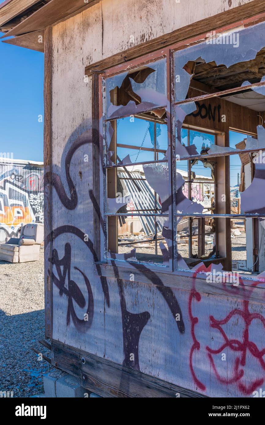 A vandalized house with broken window glass and spray painted graffiti in the settlement of Bombay Beach, California. Stock Photo