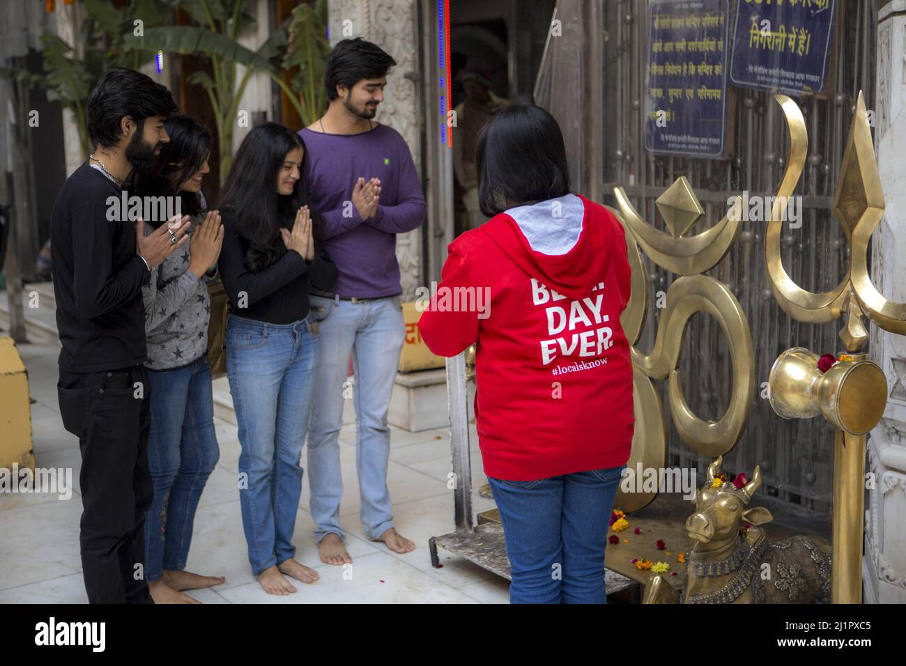 A view of men and women standing barefood in a temple and praying near hindu symbolic statues Stock Photo