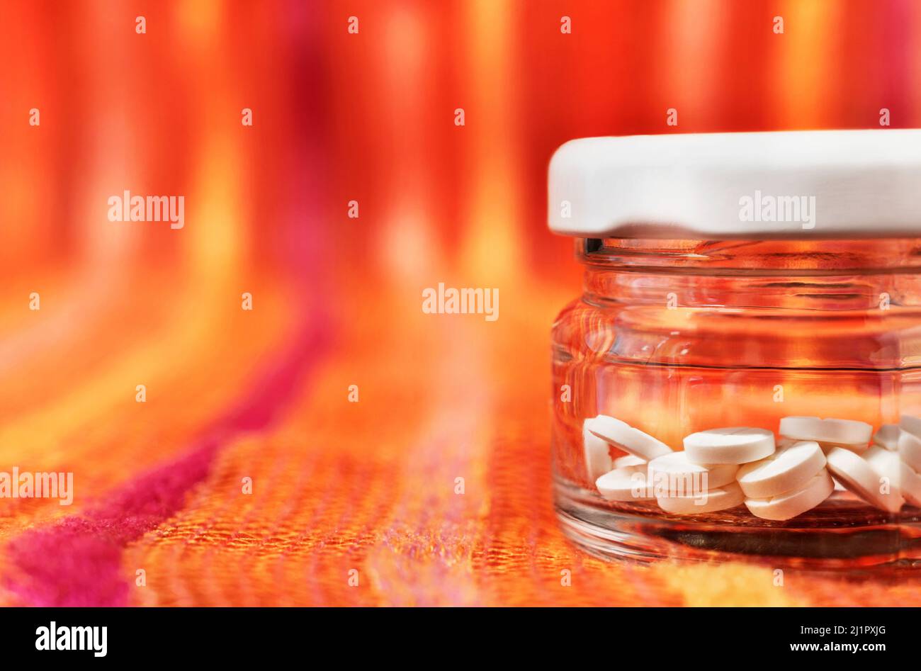 White pills in closed glass jar on colored background , hearth care  and medicine Stock Photo