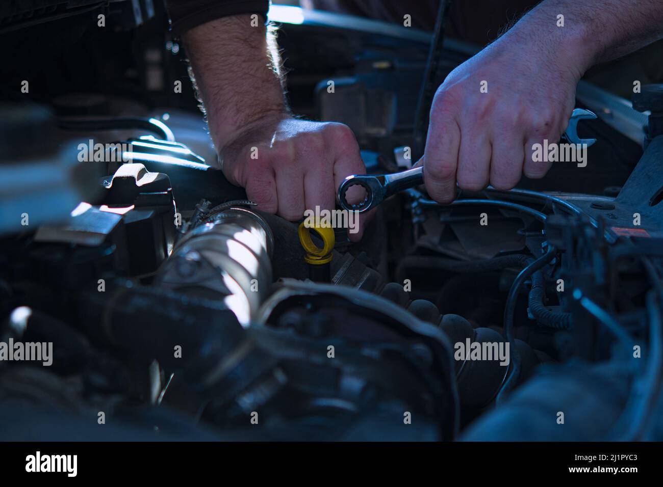 Auto mechanic working on car engine in mechanics garage. Repair service. authentic close-up shot Stock Photo