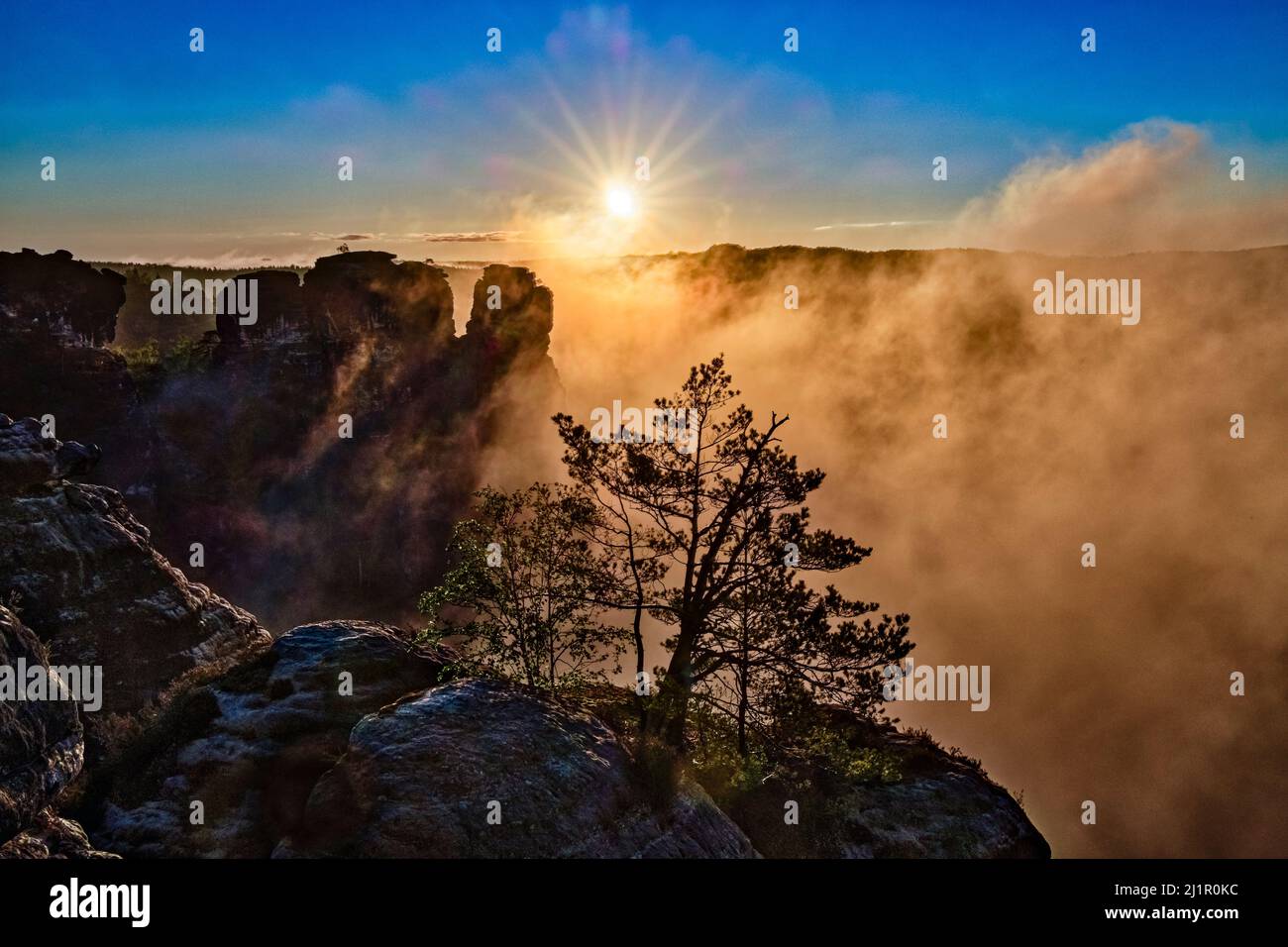 Landscape with rock formations and the Elbe valley covered in fog in Rathen area of the Saxon Switzerland National Park at sunrise. Stock Photo