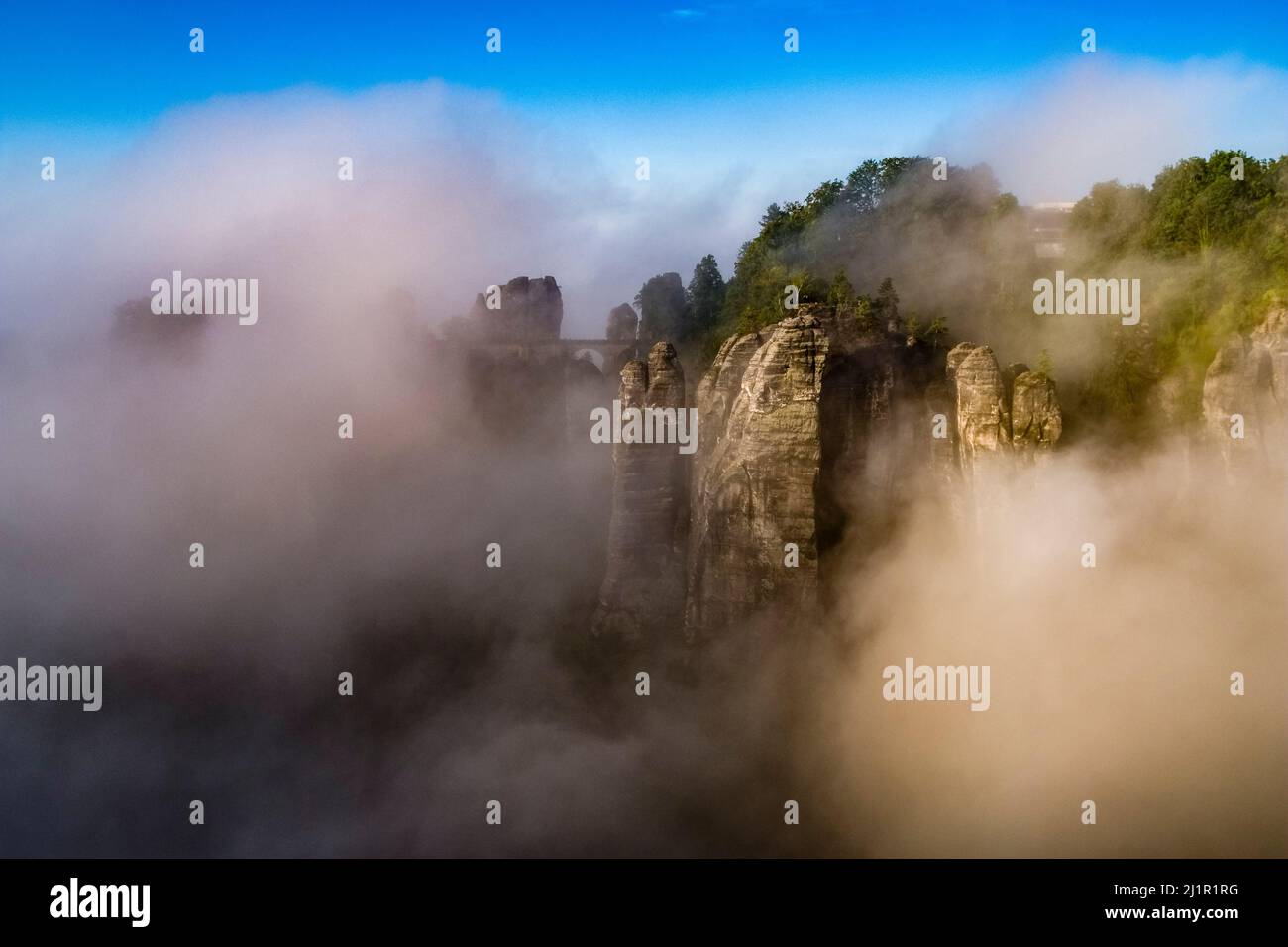Landscape with the rock formations Felsenburg Neurathen and Bastei covered in fog in Rathen area of the Saxon Switzerland National Park. Stock Photo