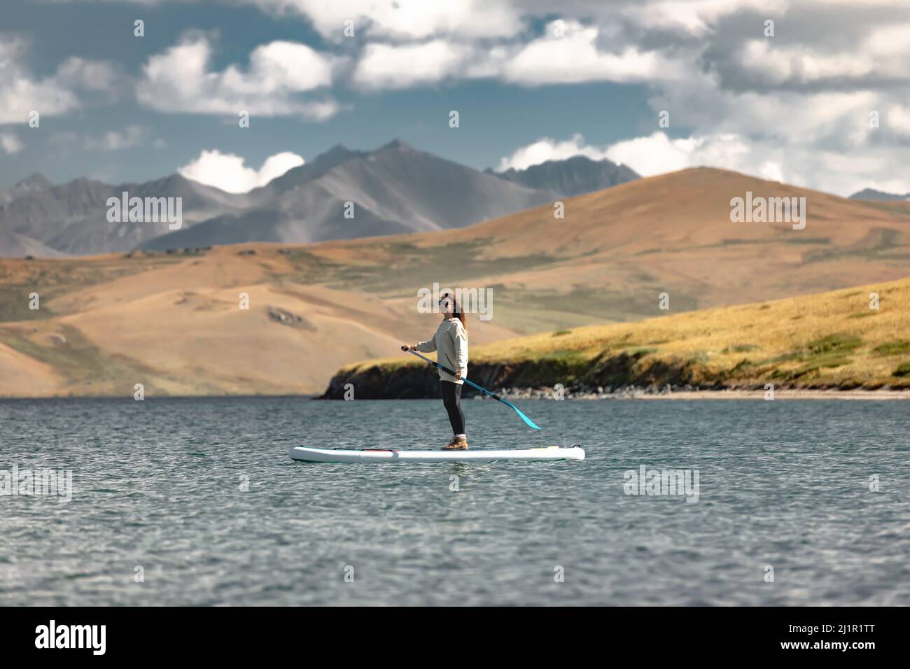 Young girl walks on stand up paddle board at mountain lake. Summer weekend concept Stock Photo