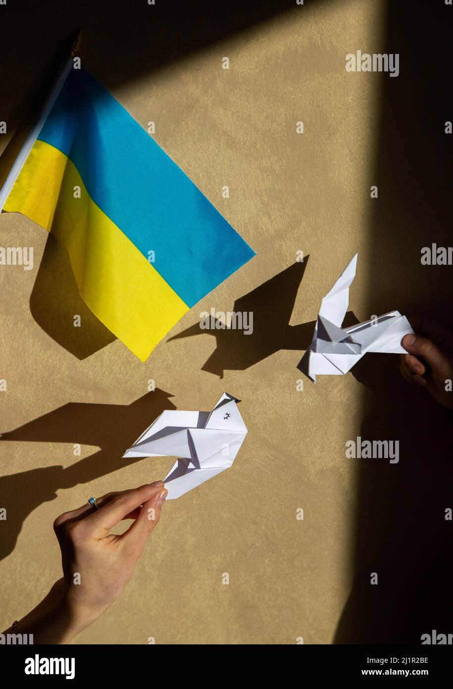 2 paper doves of peace and Ukrainian flag. Stand with Ukraine. Stop the war in Ukraine. Appeal to the world community for help. games of shadow and li Stock Photo