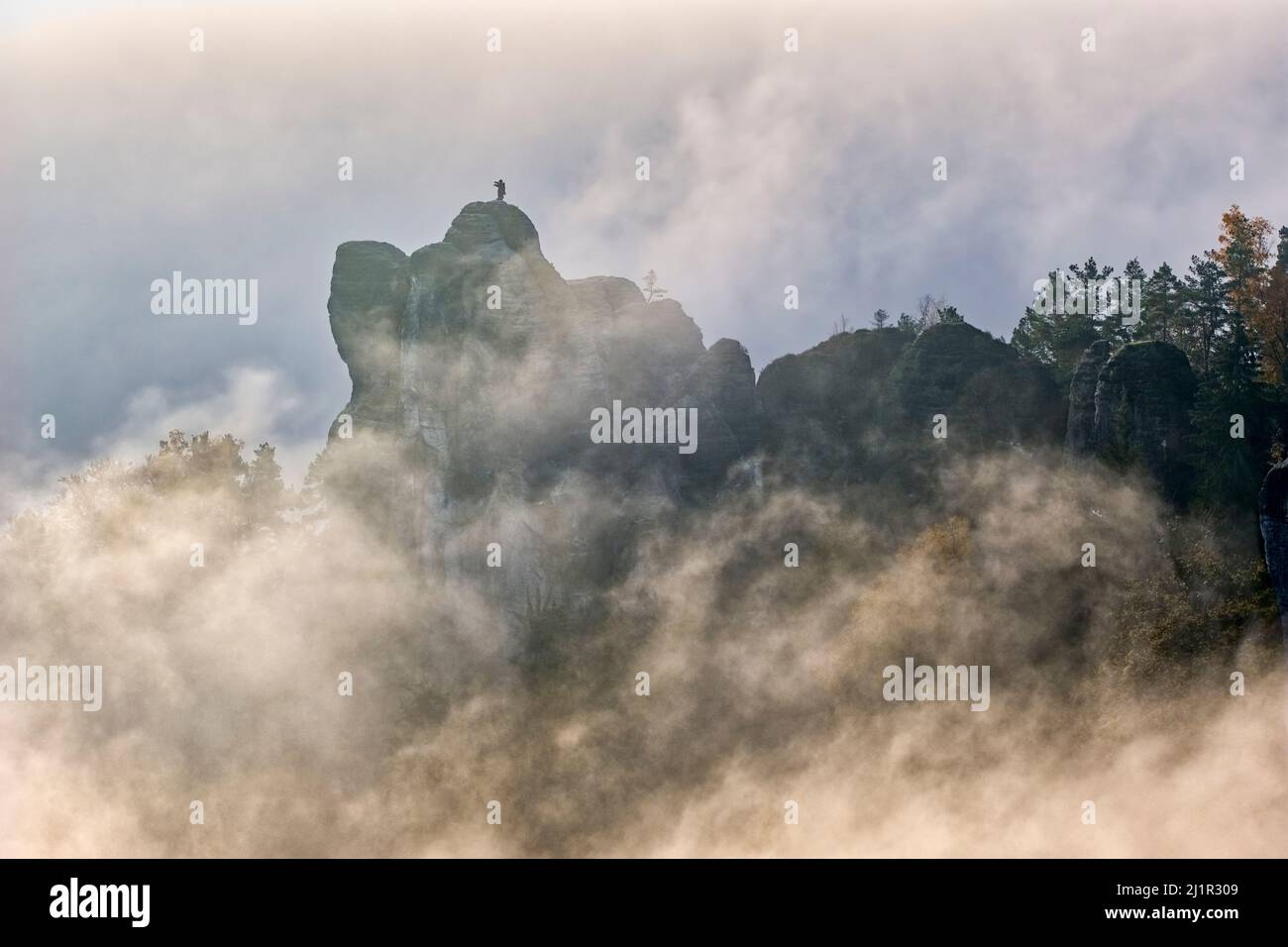 Landscape with rock formations and the summit Mönch covered in fog in Rathen area of the Saxon Switzerland National Park. Stock Photo