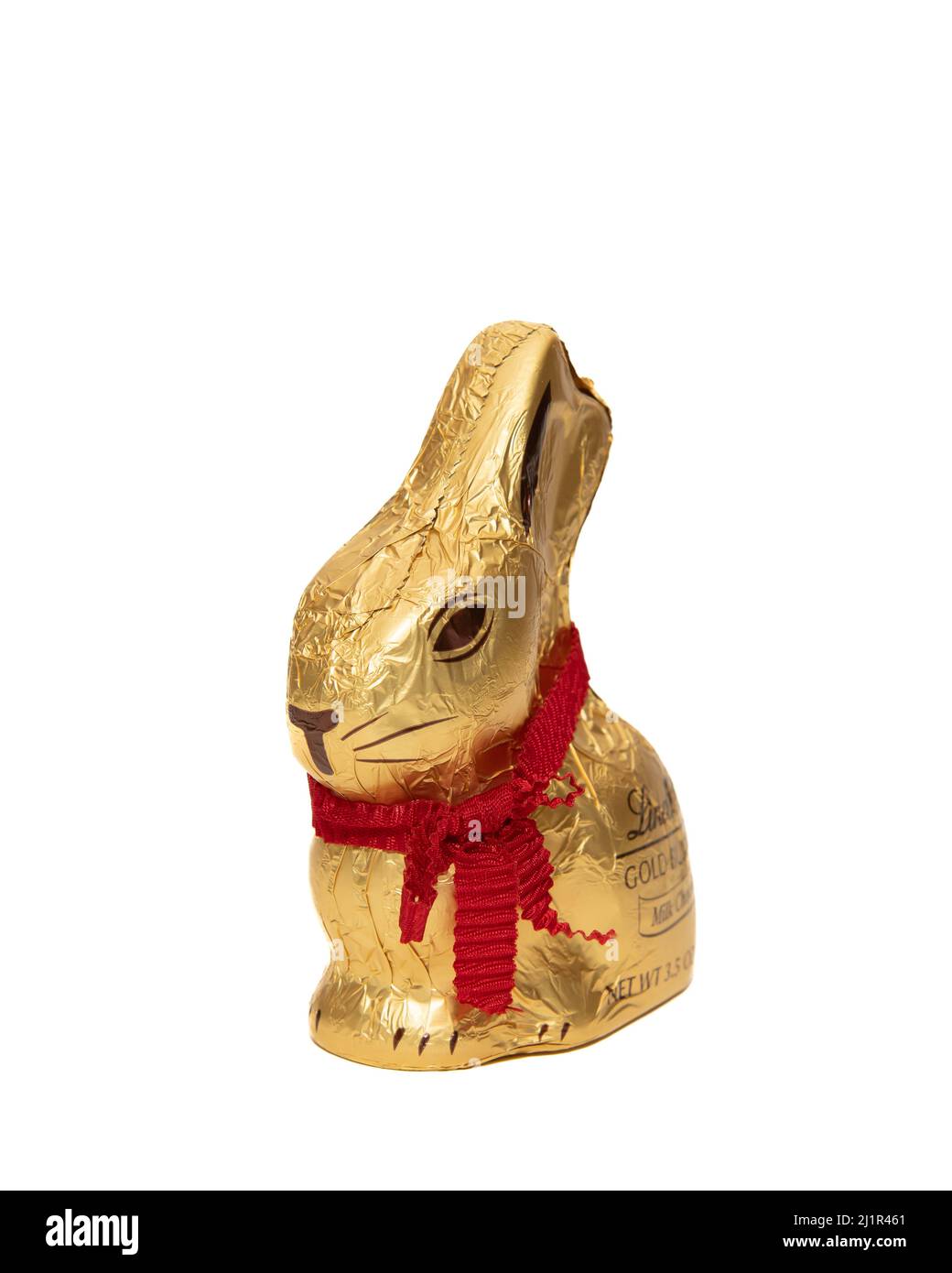 A milk chocolate Lindt Easter bunny wrapped in gold foil with a red ribbon necklace isolated on white Stock Photo