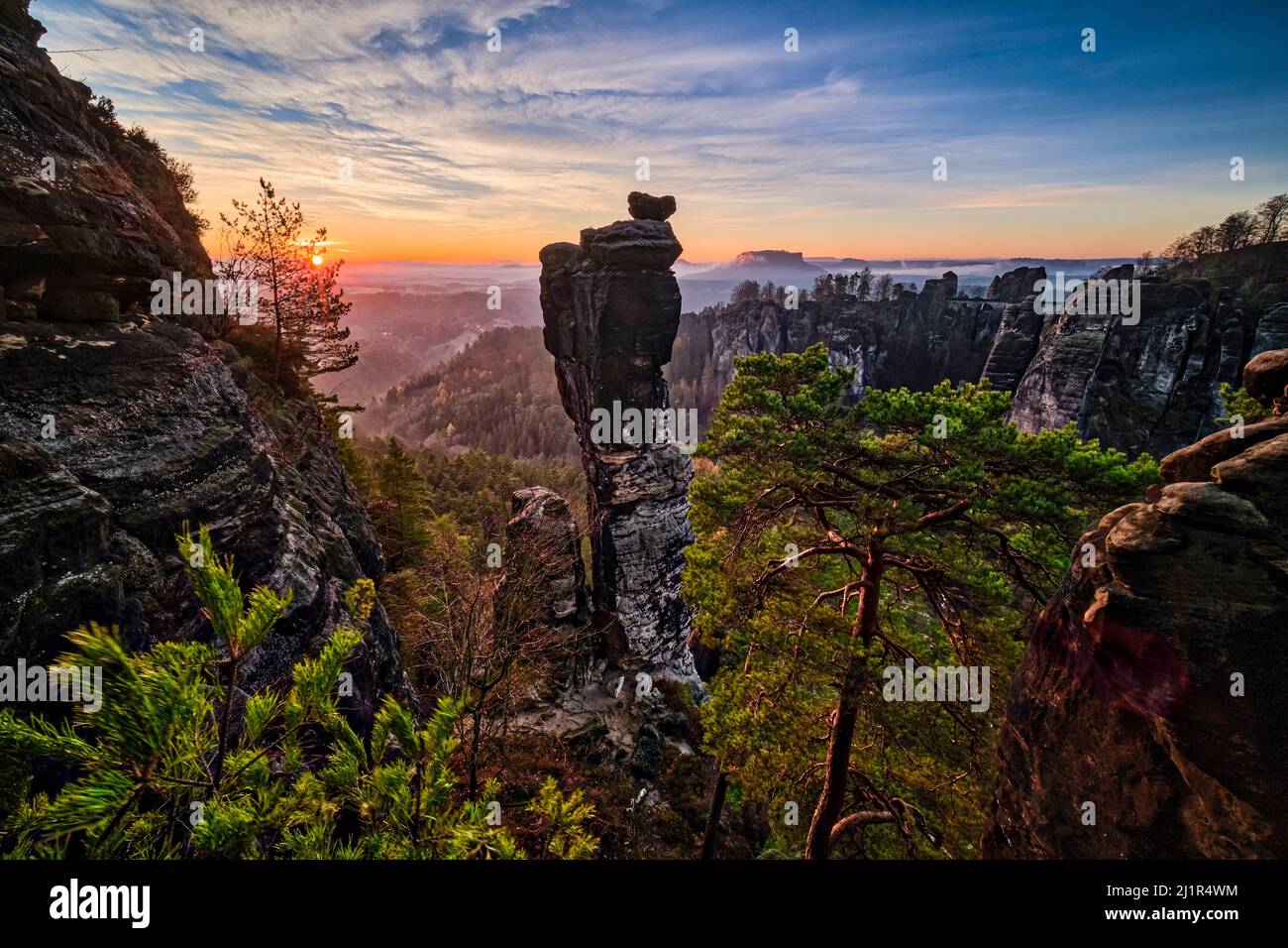 Foggy landscape with rock formations and the summit Wehlnadel in Rathen area of the Saxon Switzerland National Park at sunrise. Stock Photo