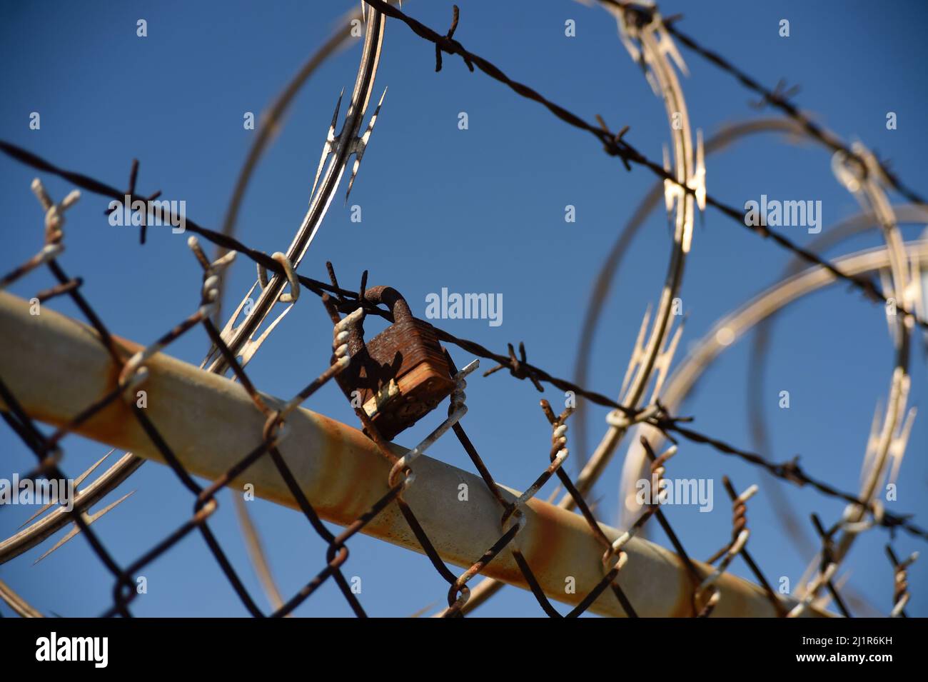 Rusty lock secured to barb wire in San Diego, California Stock Photo