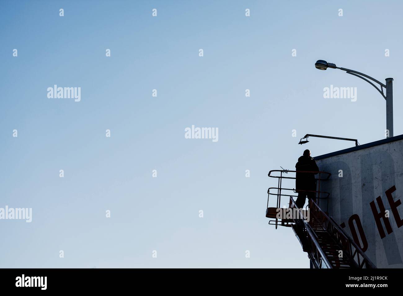 Banner by the road hang worker on a billboard.  Industrial climber working on a ladder Stock Photo