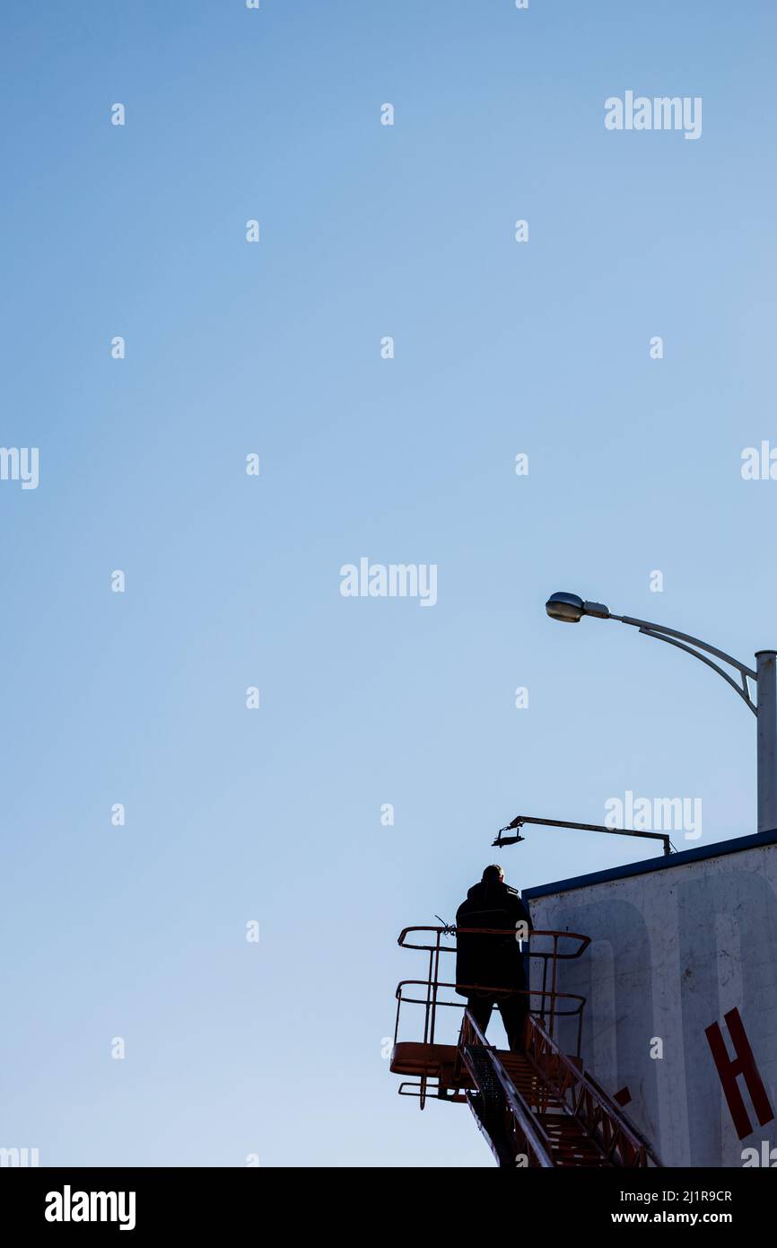 silhouette of worker install billboard on roadside. industrial mountaineering Stock Photo
