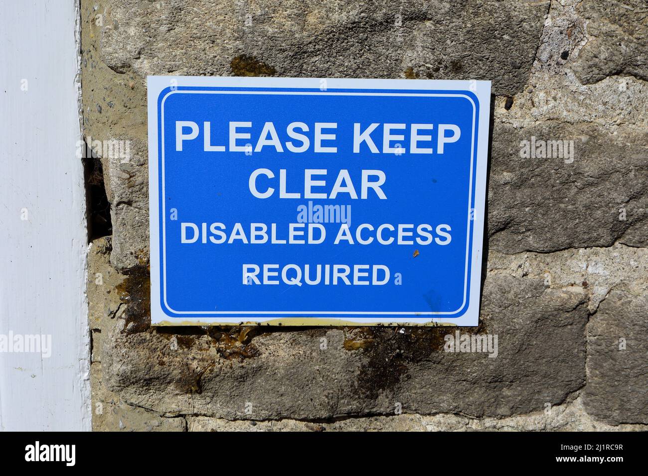 a wall mounted no parking blue rectangular sign stating 'please keep clear disabled access required' Stock Photo