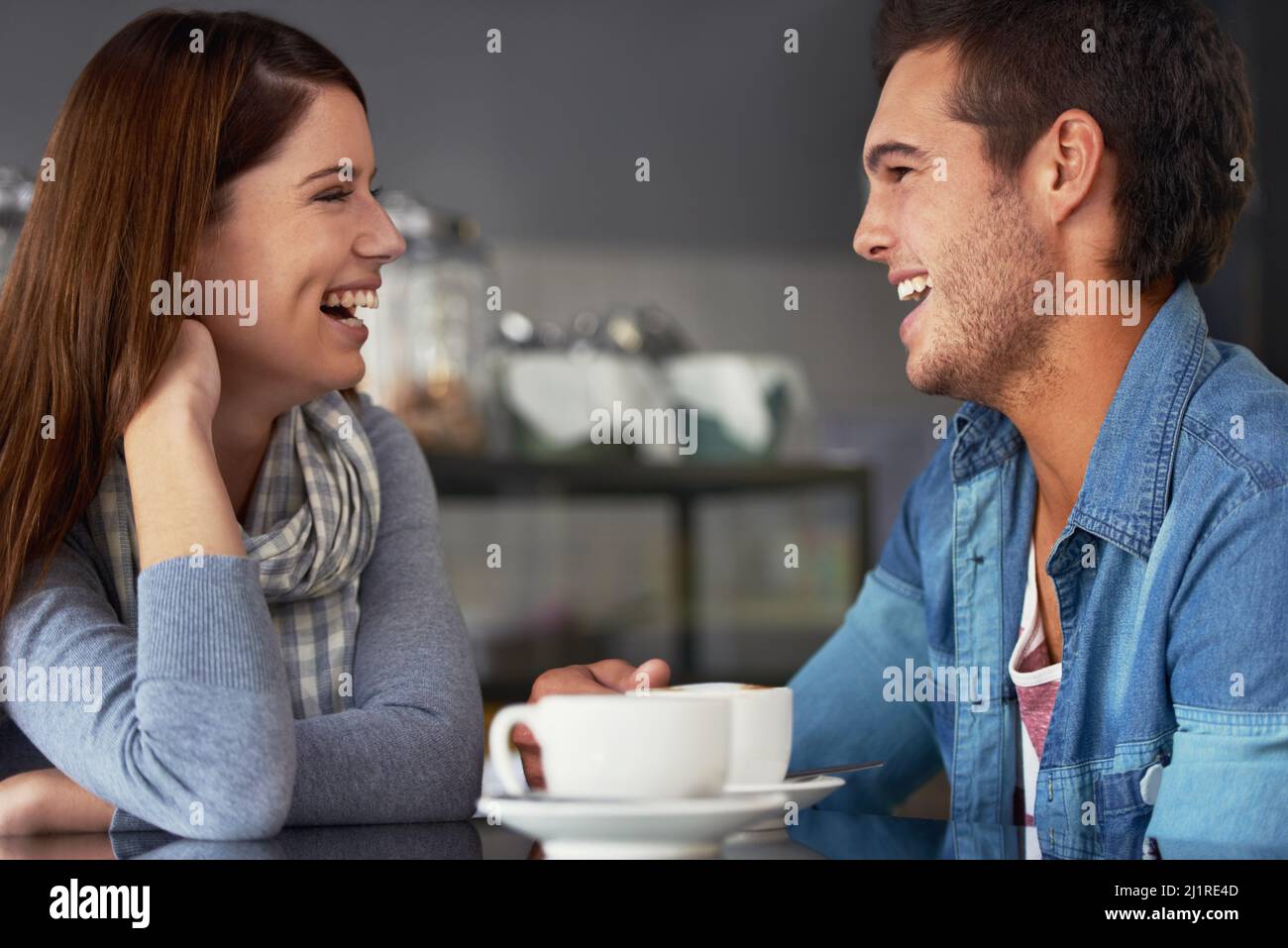 He always makes her smile. A loving young couple at a coffee shop together. Stock Photo