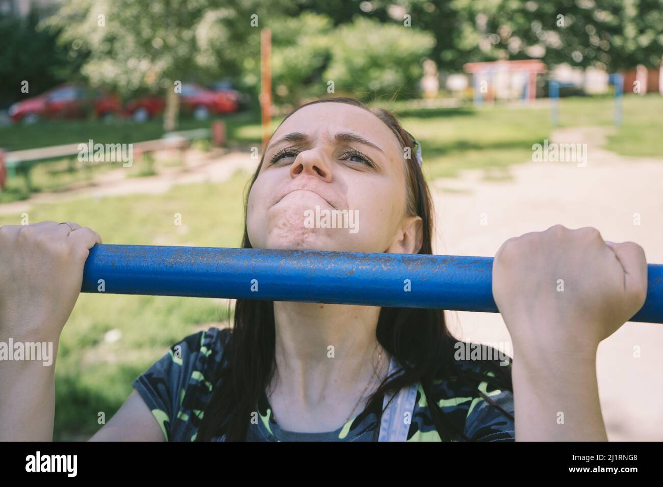 young female doing pull ups on horizontal bar outdoors Stock Photo - Alamy