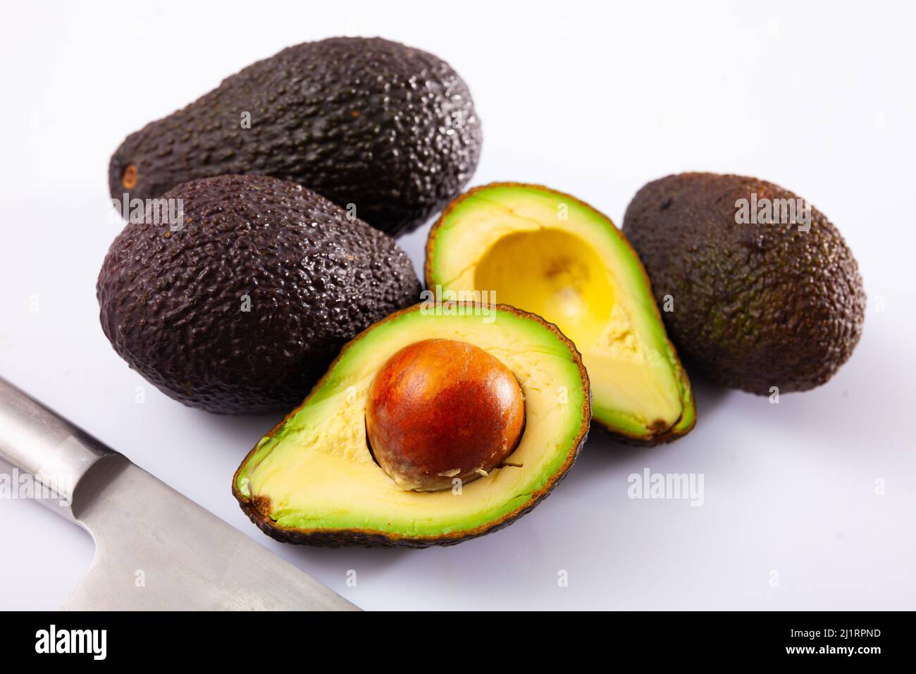 Whole and cut in half Hass avocados on white Stock Photo - Alamy