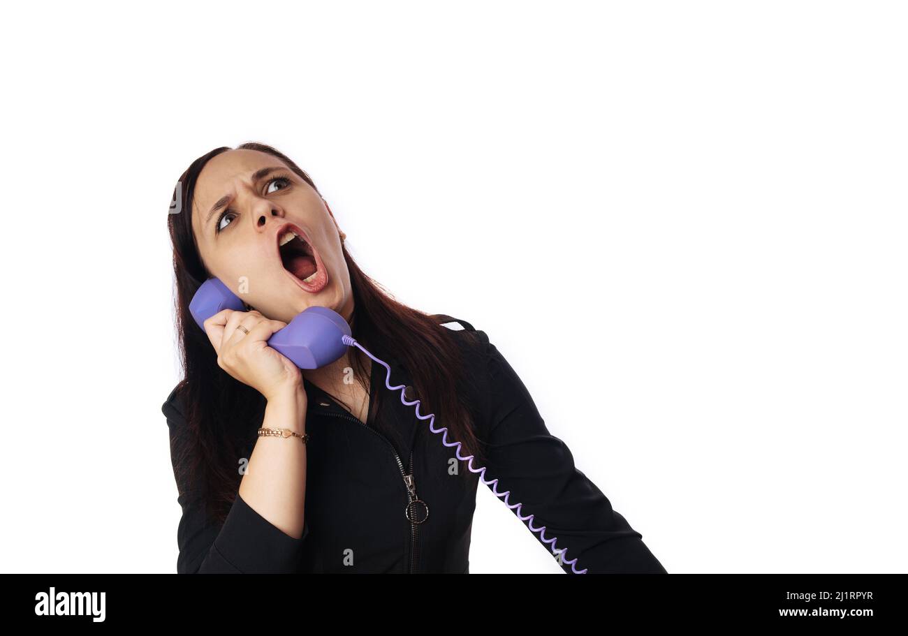 A beautiful young woman in a black dress grimaces, talking on home phone. Stock Photo