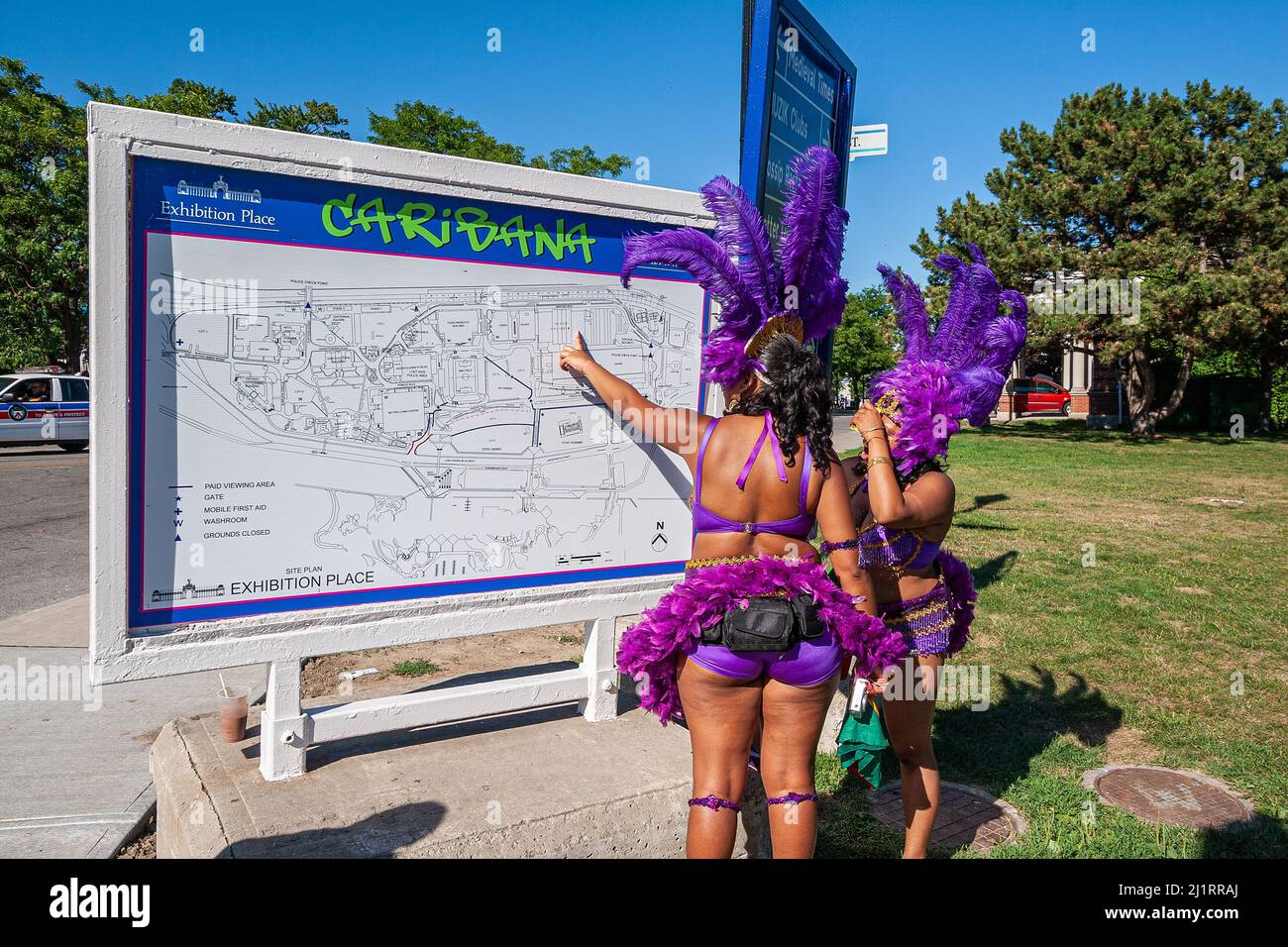 Toronto, Ontario - Caribana festival female participants in colourful costumes looking for directions at the route map of the parade Stock Photo