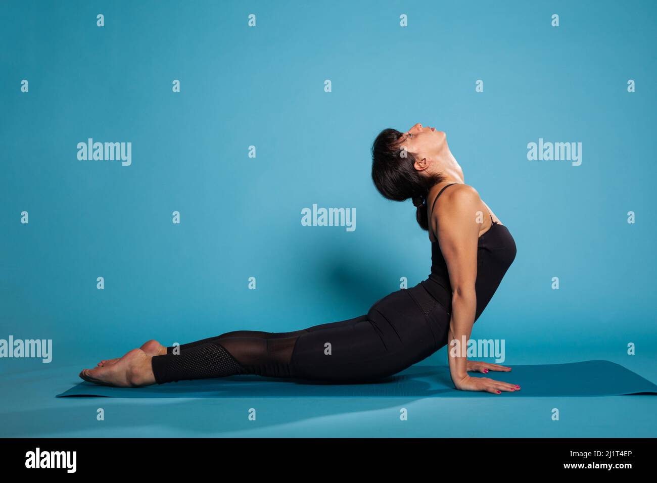 Fitness woman sitting on yoga mat in dog backbend pose stretching back during pilates workout. Personal trainer in sportswear training body muscles working at body endurance. Sport concept Stock Photo...