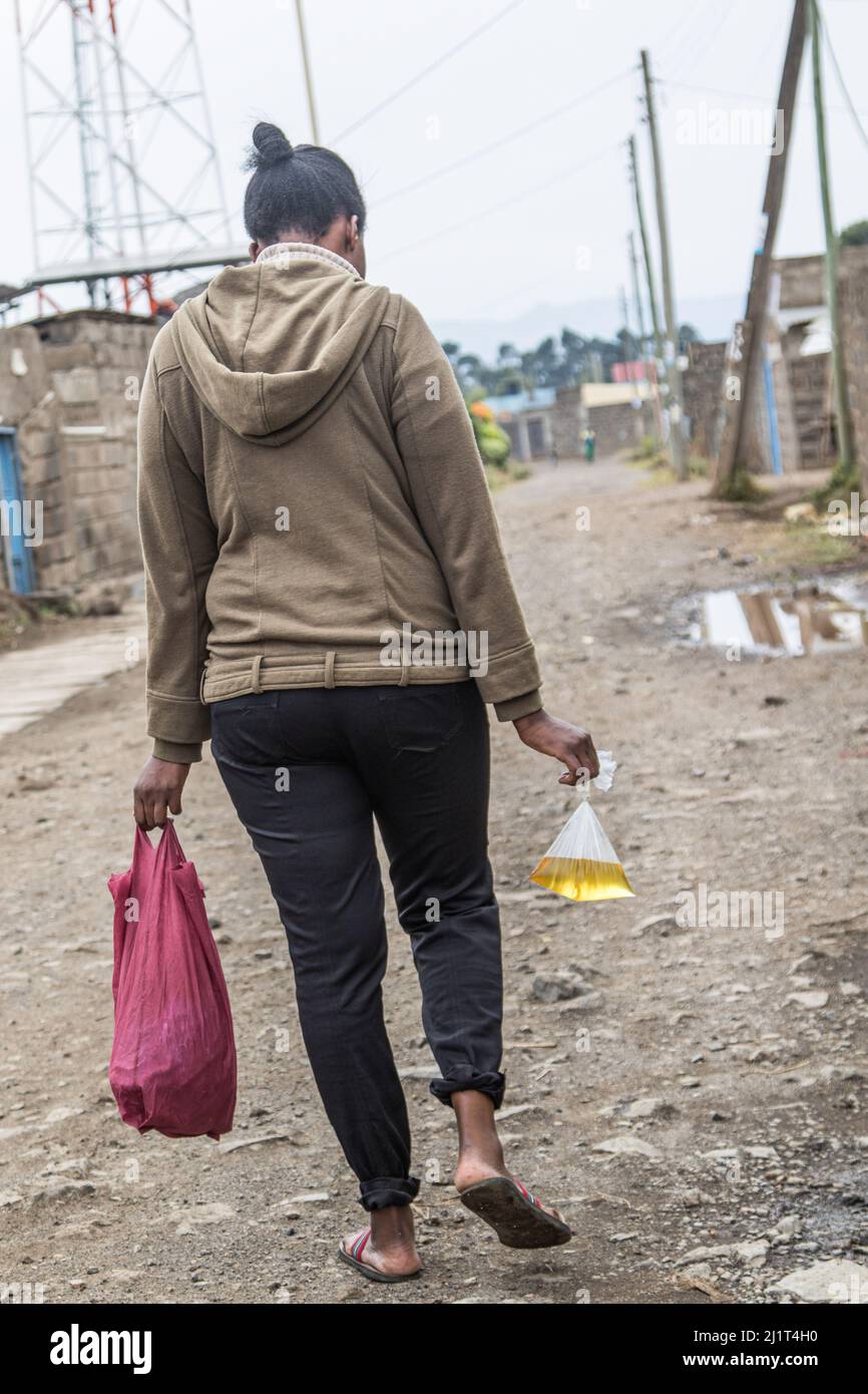 A young woman is seen carrying cooking oil packed in a banned plastic