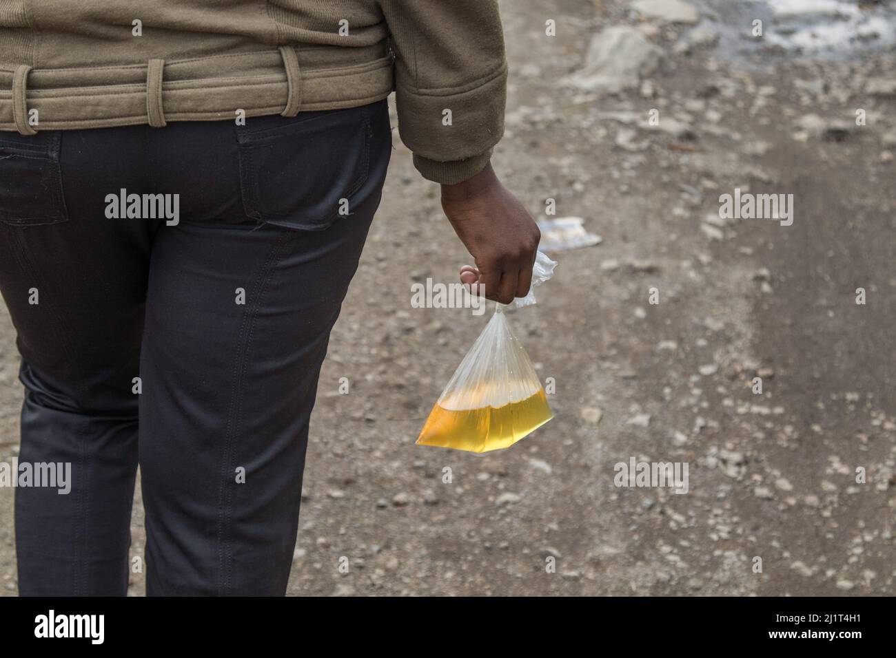 A young woman is seen carrying cooking oil packed in a banned plastic