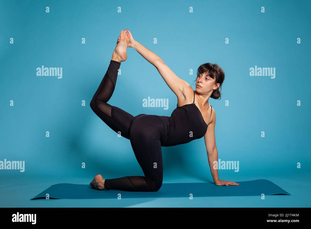 Active trainer sitting on yoga mat stretching leg training body muscles