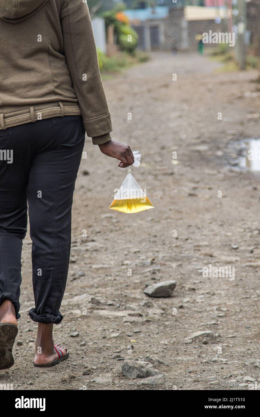 A young woman is seen carrying cooking oil packed in a banned plastic