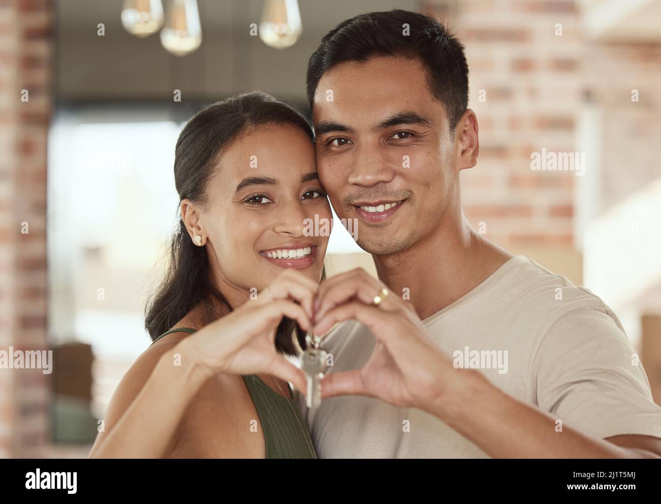 Love is what makes a home. Shot of a young couple forming a heart shape ...