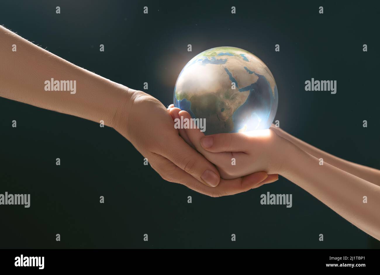 Child and adult holding planet in hands on dark background. Earth day ...