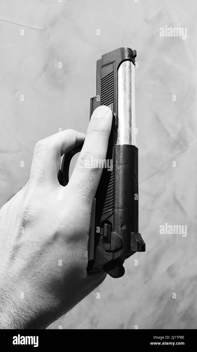 A grayscale shot of a malehand holding a shotgun Stock Photo