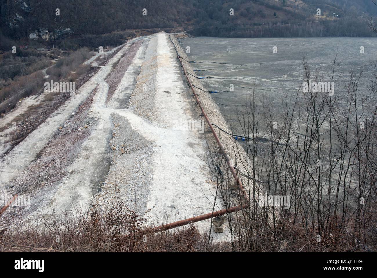 Barrier stopping the flow of copper and gold mining mining residuals into a settling basin, decantation lake. Geamana, Rosia Montana, Romania Stock Photo