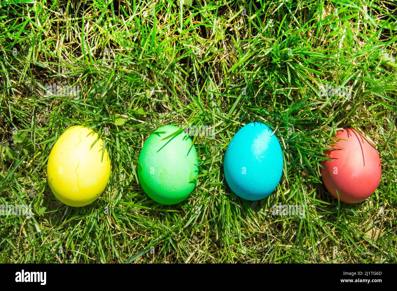 Four painted and decorative Easter eggs in the grass. Top view, copy space Stock Photo