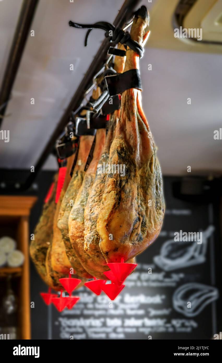 Whole bone-in legs of Spanish serrano iberico ham on display at a restaurant in San Sebastian Donostia, Basque Country, Spain Stock Photo