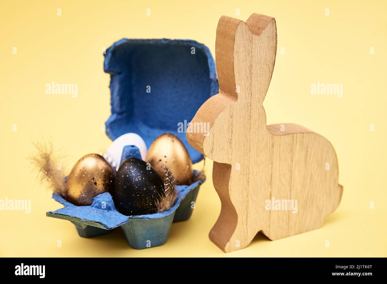 Wooden rabbit and colored eggs on yellow background, Happy Easter card Stock Photo