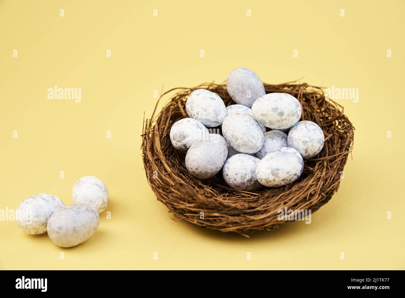 Nest with small eggs on yellow background, Happy Easter card Stock Photo