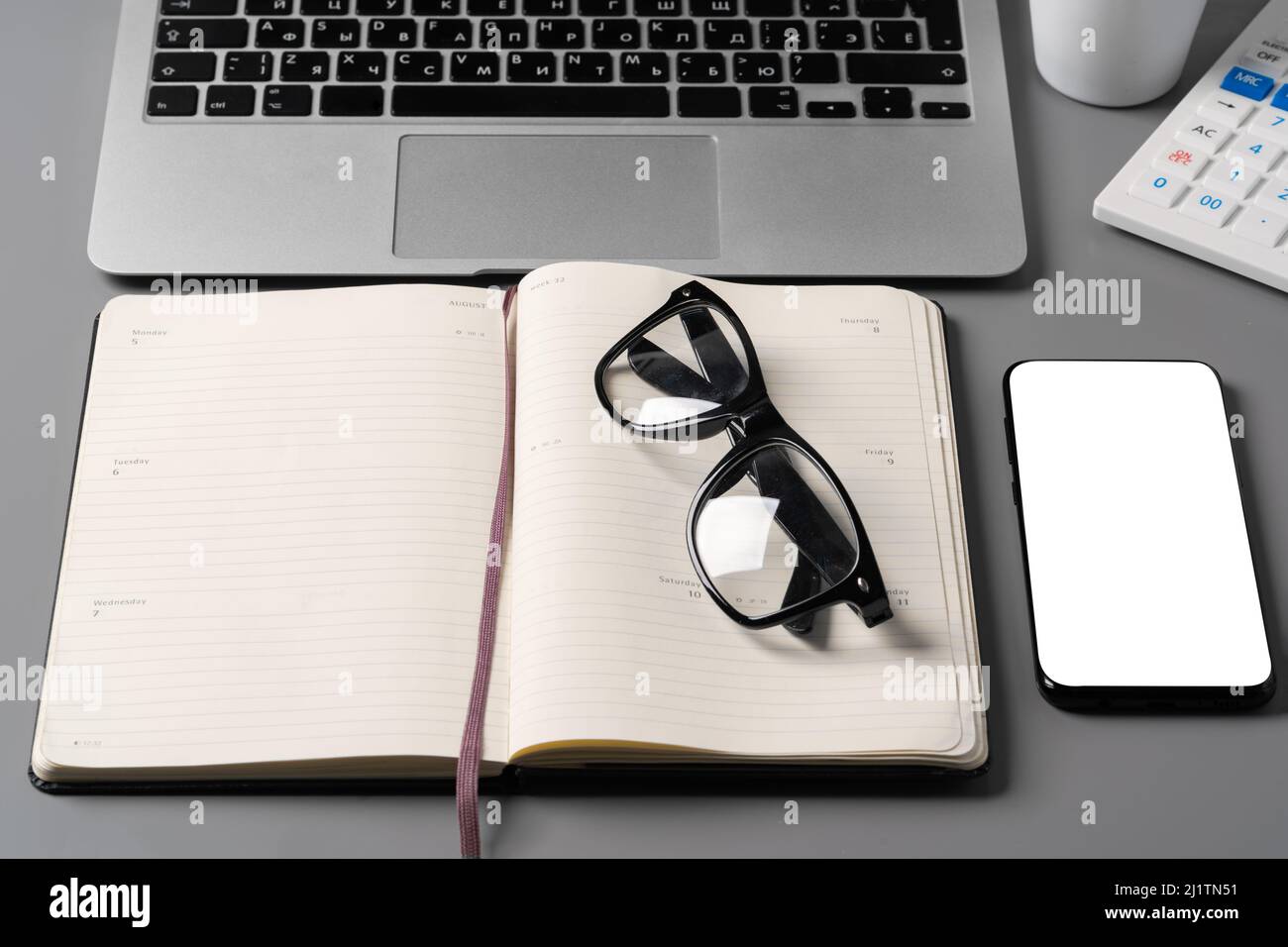 Notepad is on top of office desk table with laptop and supplies Stock