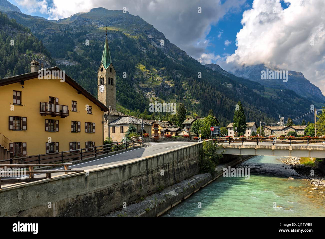 Bridge over mountain river along houses and old church on background in small town of Gressoney-Saint-Jean in Aosta Valley, Italy. Stock Photo