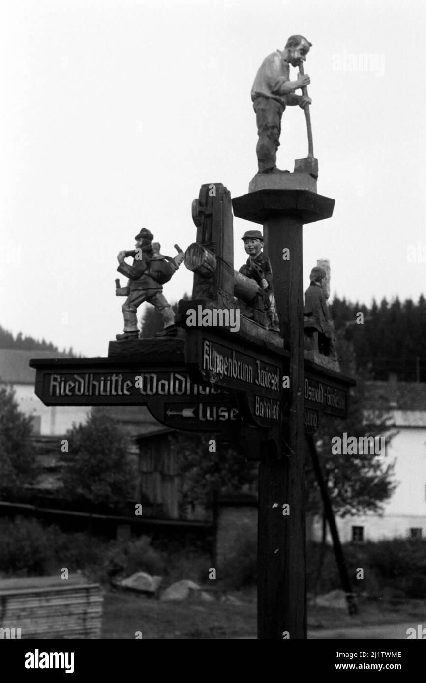 Aus Holz geschnitzer Wegweiser im Bayerischen Wald, 1965. Wood-carved signpost in the Bavarian Forest, 1965. Stock Photo