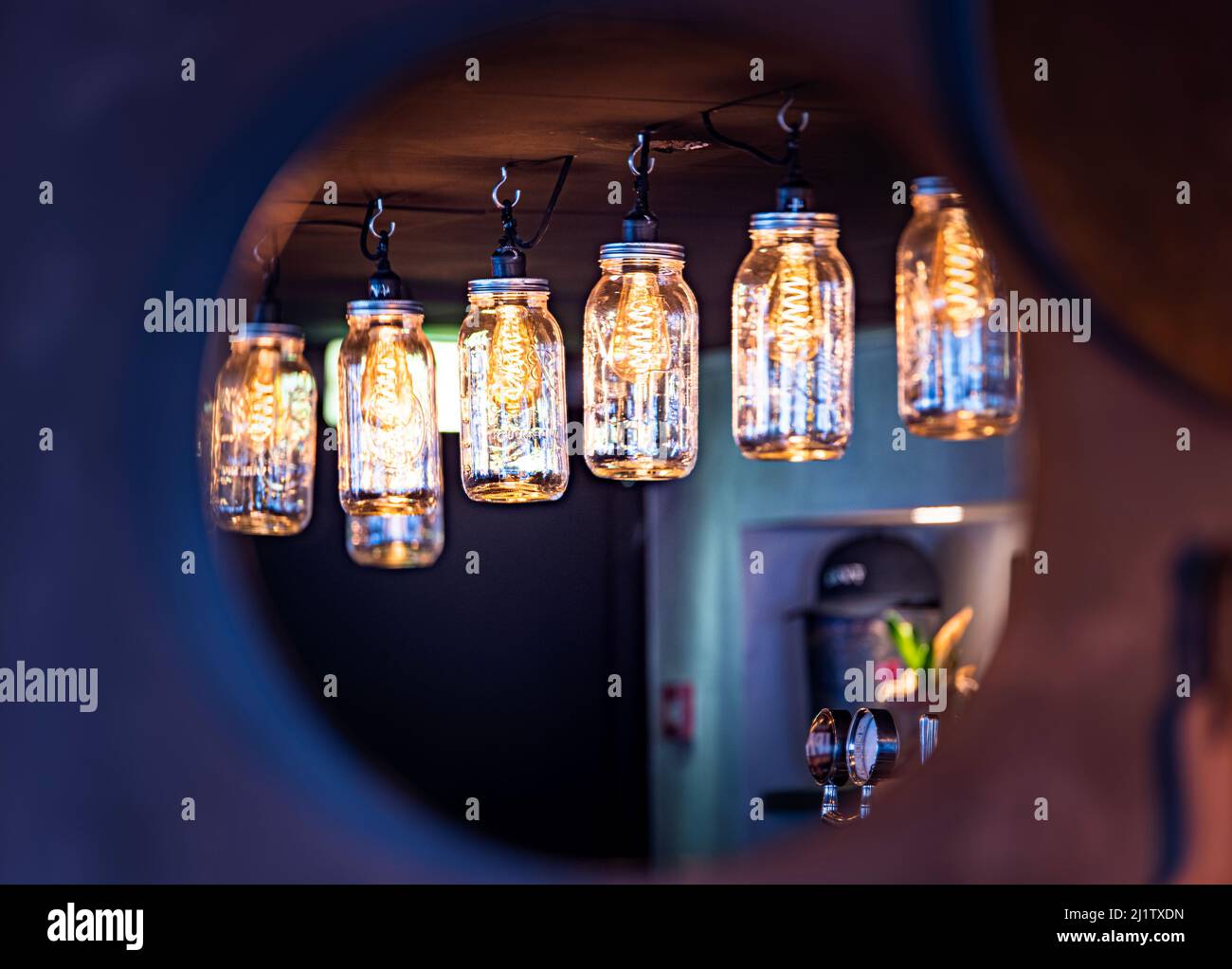 Industrial pub interior with cosy hanging lights in glass boxes through a circular mirror. Industrial interior architecture design with ceiling lights Stock Photo