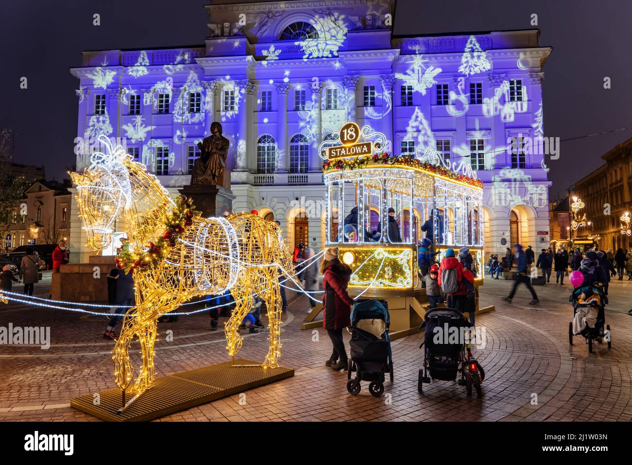 Warsaw, Poland - December 12, 2020: People enjoy horse and vintage tram holiday illumination at Staszic Palace and Nicolaus Copernicus monument at nig Stock Photo