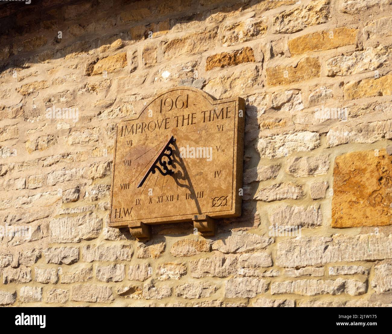 Sundial with the inscription 1961 Improve The Time, on the stone wall of an old cottage, Courteenhall, Northamptonshire, UK Stock Photo