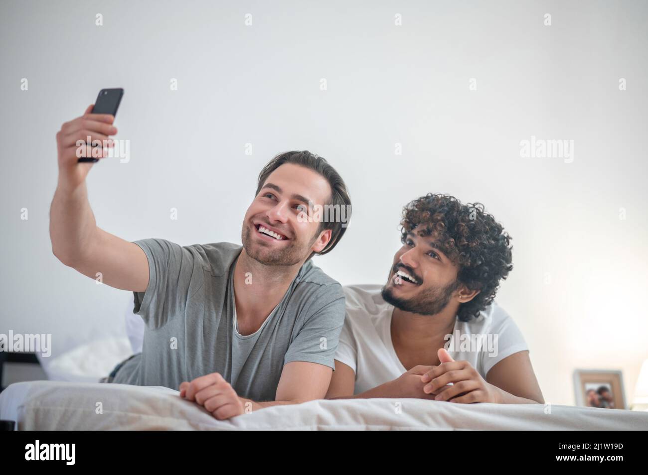 Two gay men taking selfies in the bedroom Stock Photo