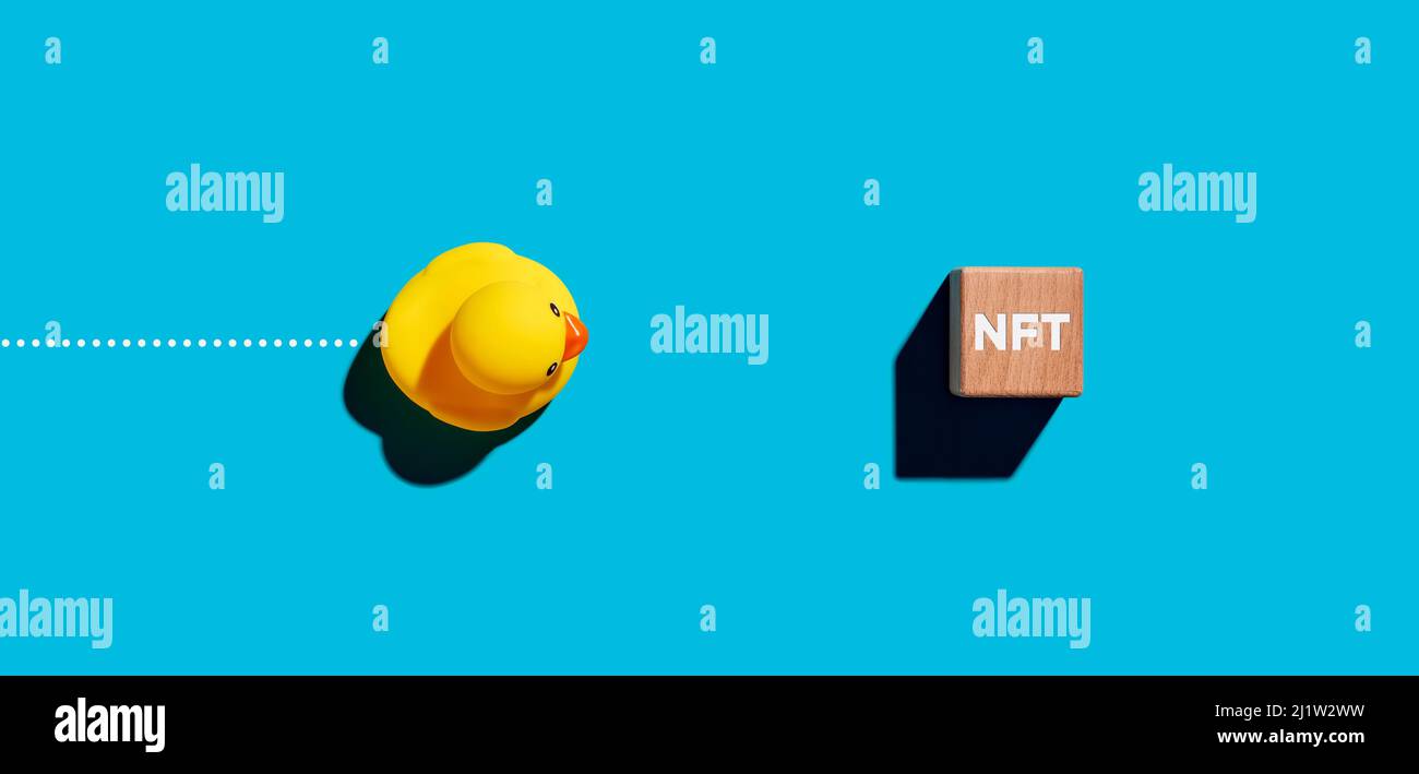 Toy robber duck moves towards a wooden cube with the acronym NFT for non  fungible token cryptocurrency. Business finance concept Stock Photo - Alamy