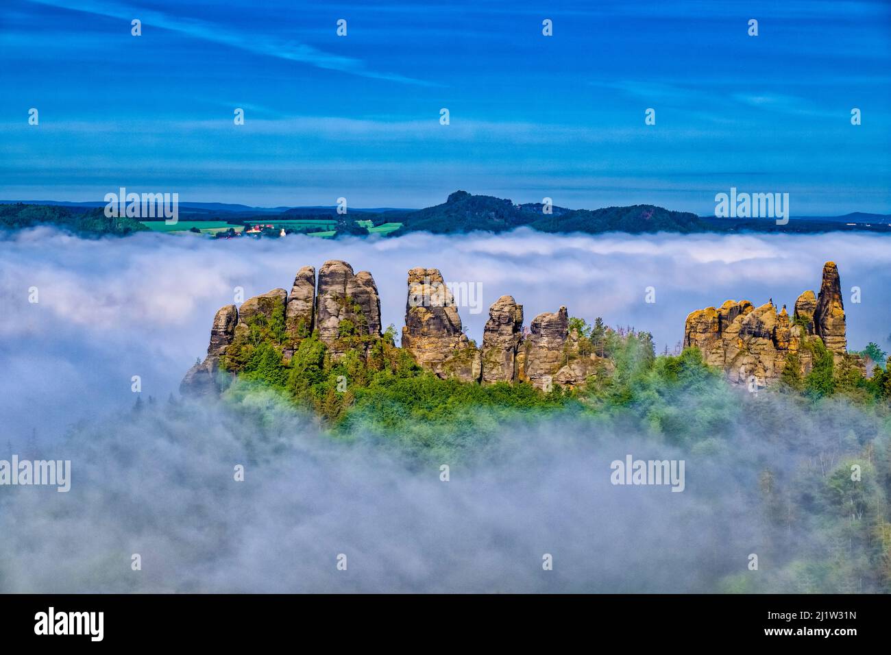 Landscape with rock formations and the Elbe valley covered in fog in Schrammsteine area of the Saxon Switzerland National Park at sunrise. Stock Photo