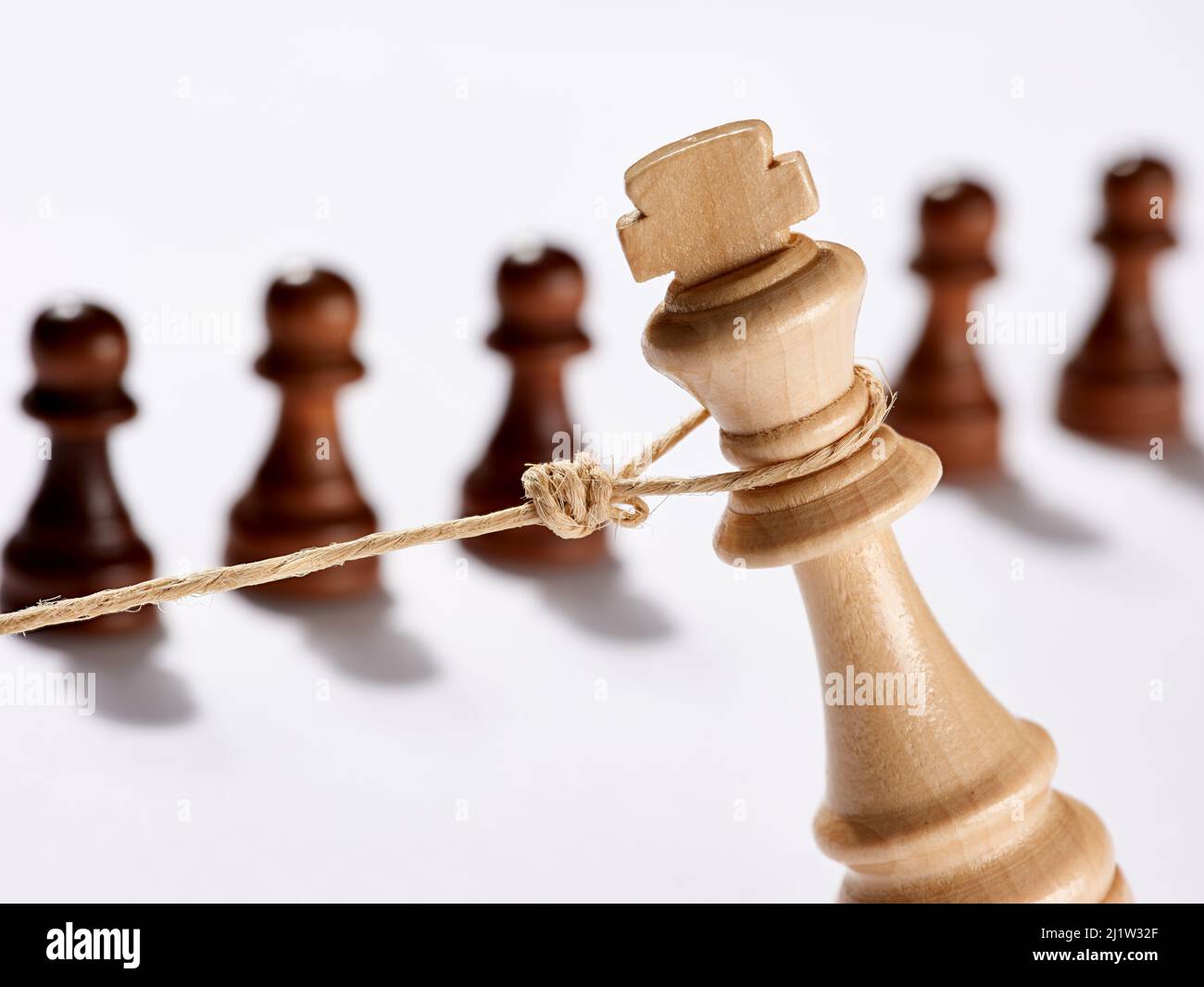 Chess piece king is pulled down by a rope in front of the rival pawns. Revolution, justice, execution and punishment concept. Stock Photo