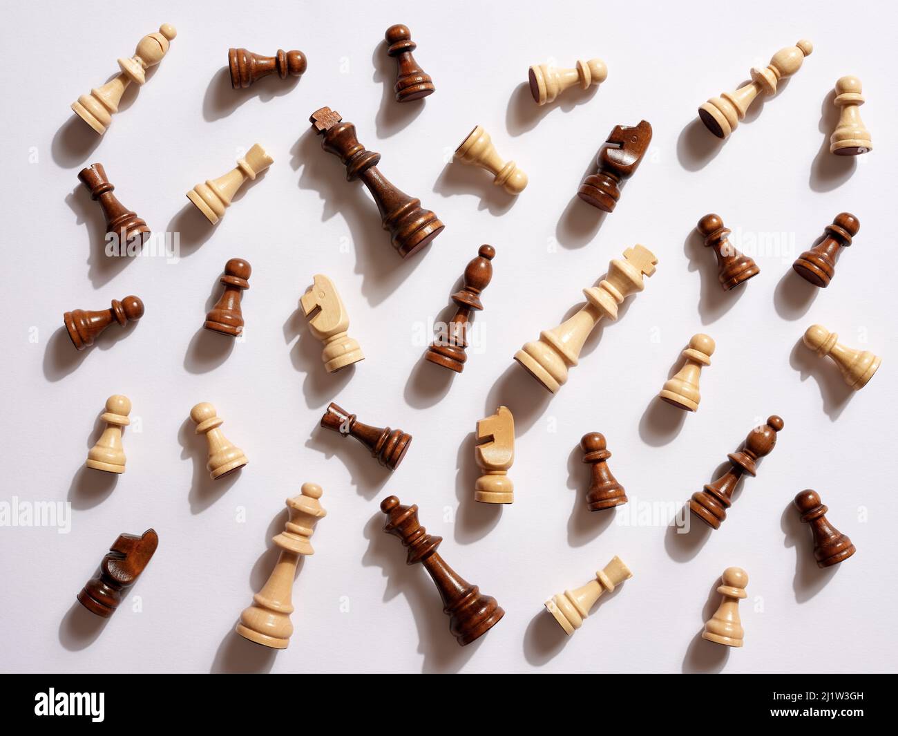 Top view of white and brown wooden chess pieces fallen on white background. Stock Photo