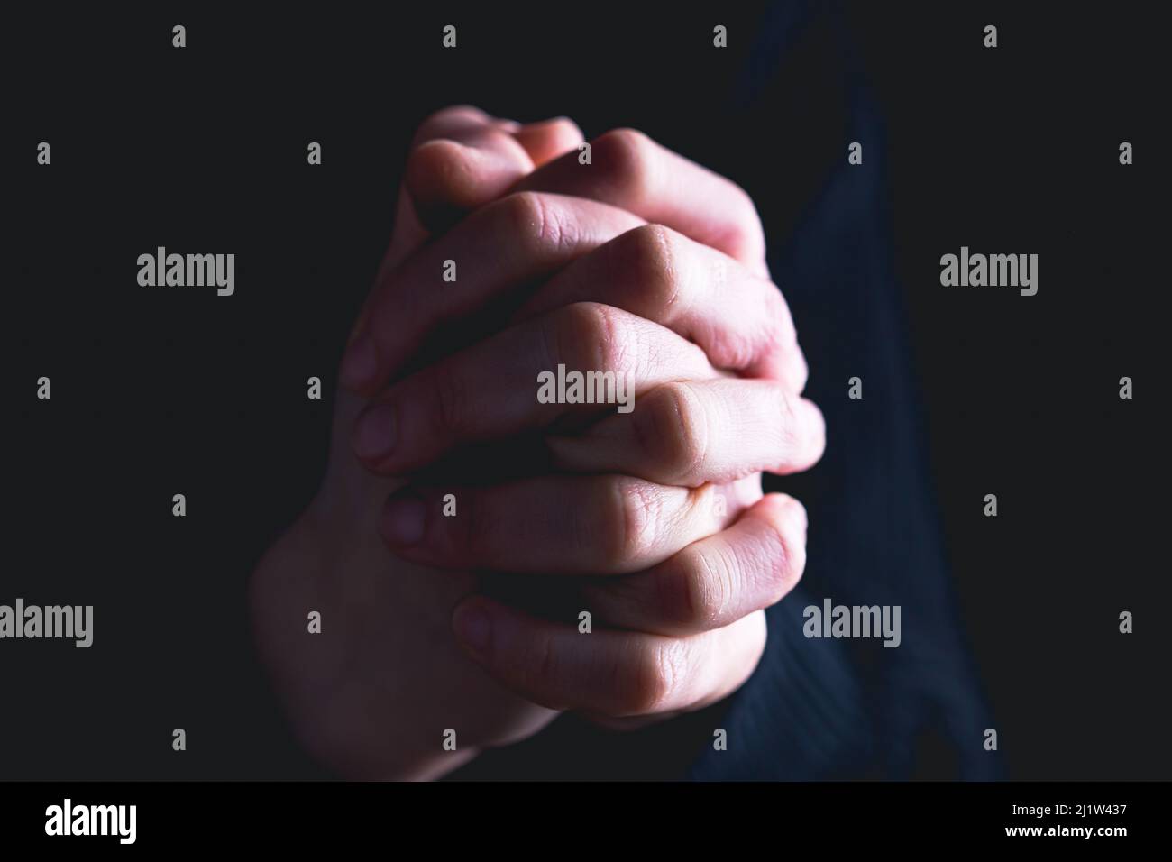 Praying hands with faith in religion and belief in God on dark ...