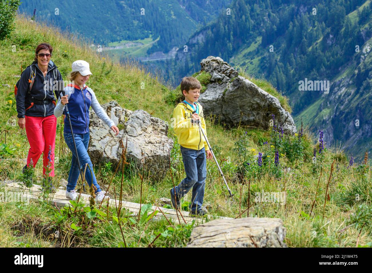 Woman hiking with a group of children in the alpine region around Warth ...