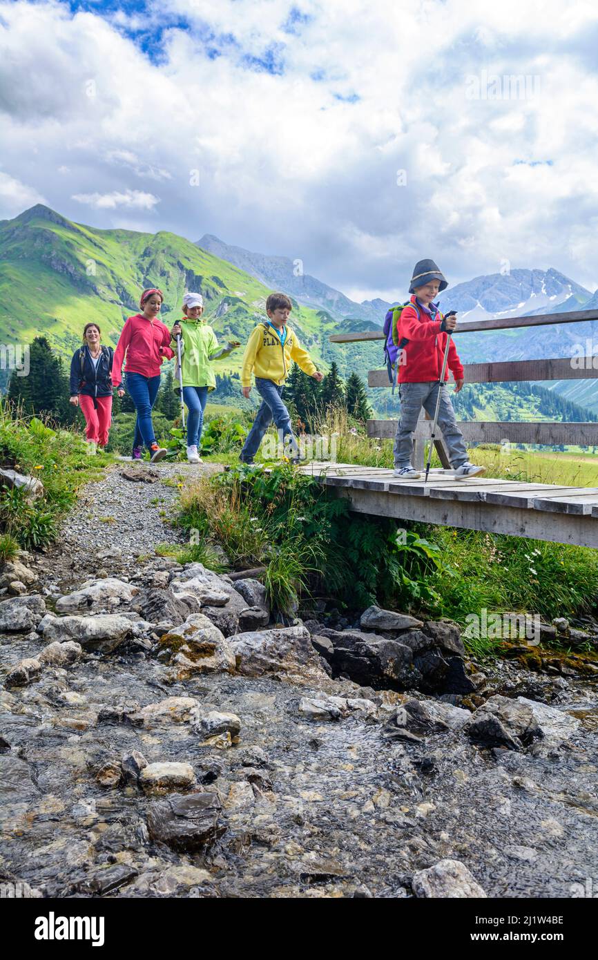 Woman hiking with a group of children in the alpine region around Warth ...