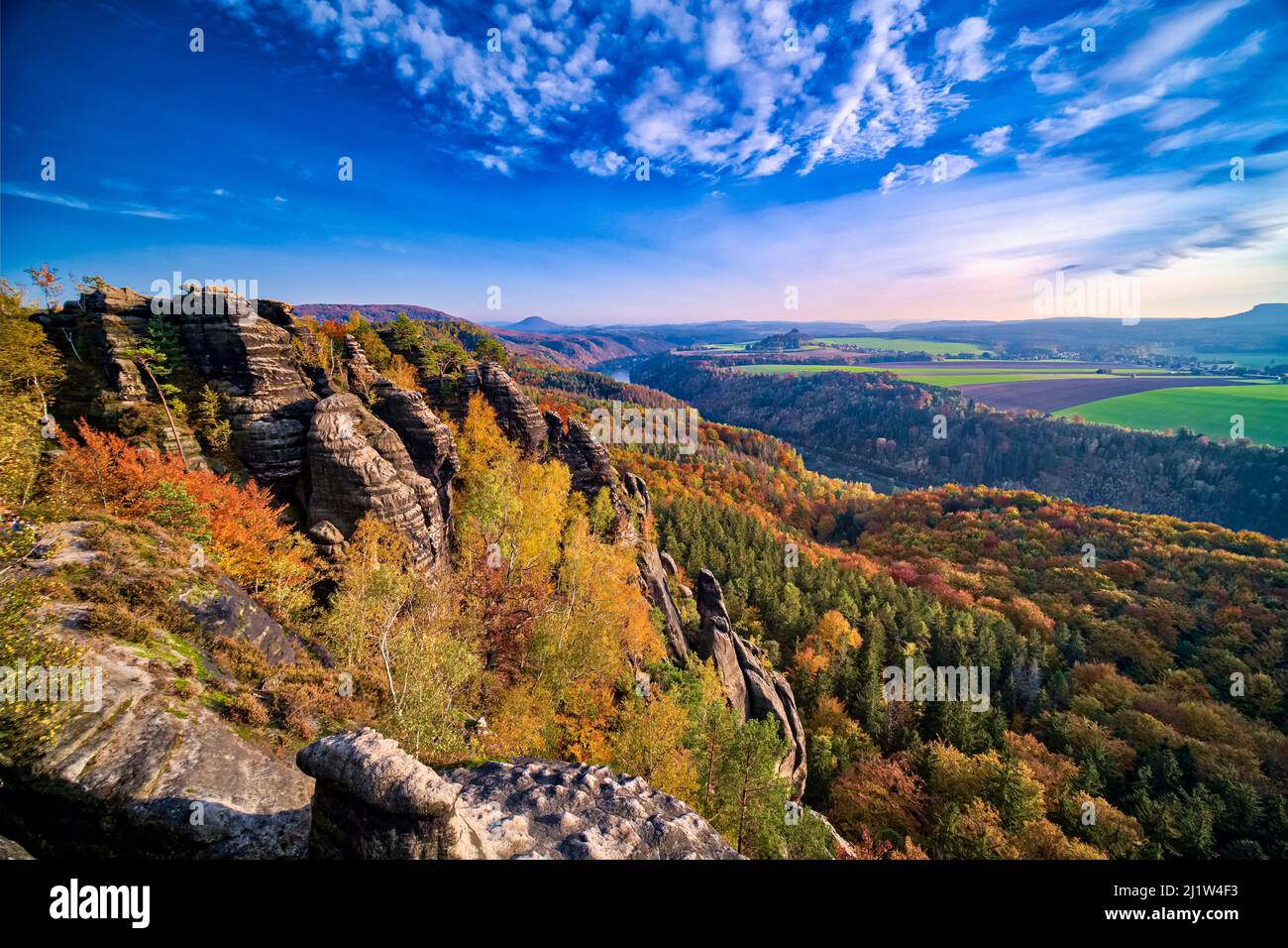 Landscape with rock formations, colorful trees and the Elbe valley in Schrammsteine area of the Saxon Switzerland National Park in autumn. Stock Photo