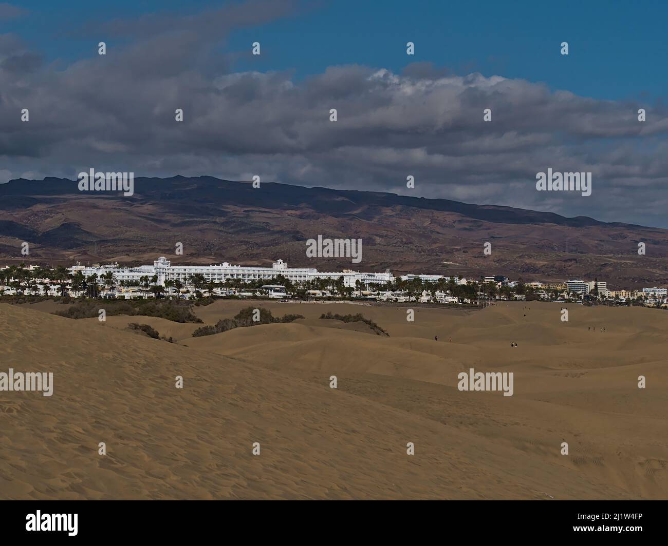 Beautiful landscape of nature reserve Dunas de Maspalomas in San Bartolome de Tirajana, southern Gran Canaria, Spain on sunny day with large hotel. Stock Photo