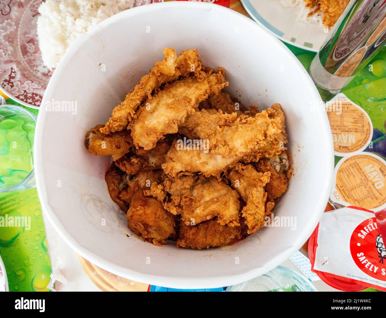 Pieces of fried chicken in a tub on a dining room table. Stock Photo